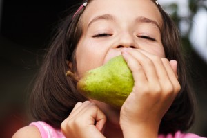 Young girl with fresh green pear outdoor