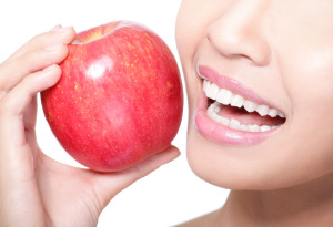 Beautiful young woman eating red apple with health teeth. Isolated over white background, asian beauty model